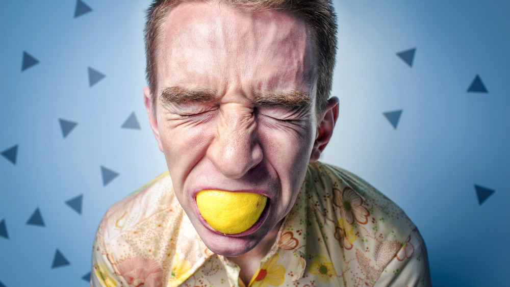 Ein Mann beißt in eine Zitrone (Symbolbild): eine finanzielle Rücklage hilft, wenn dir das Leben sauer mitspielt